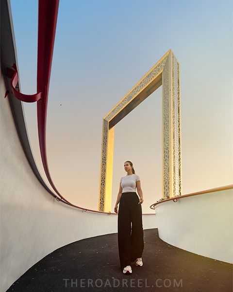 a girl posing on the sidewalk under Dubai Frame, perfect spot for a photoshoot.