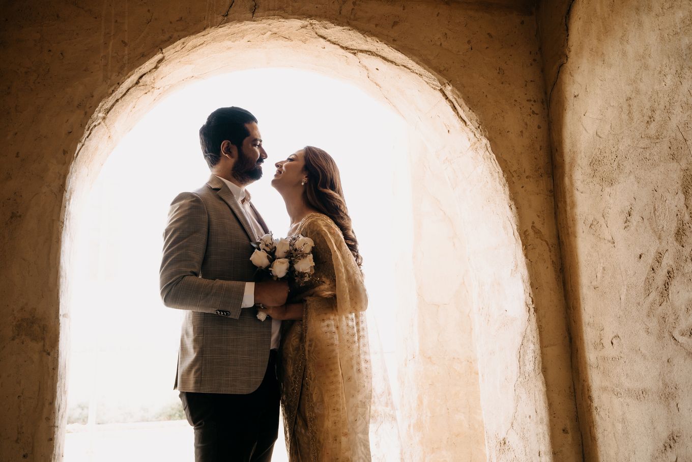 couple standing close facing each other, girl holding some flowers in her hand