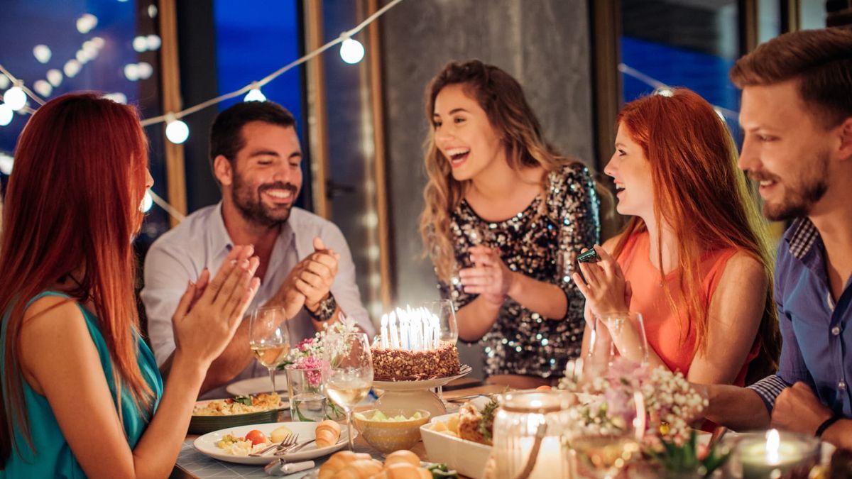 Birthday party photographer in Dubai capturing guests sitting around a table with cake, candles and dinner