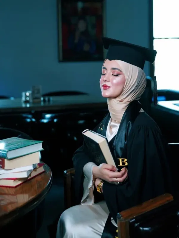 Female graduate wearing a graduation gown and holding books during a graduation photoshoot in Dubai