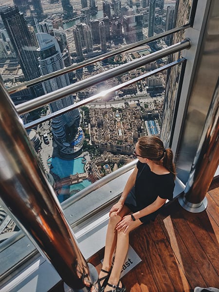 daytime city view from Borj Khalifa in Dubai with a lifestyle shoot from a woman